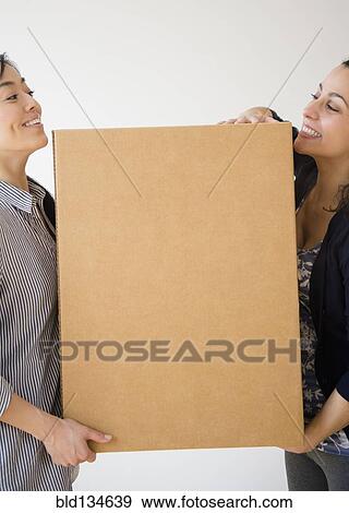 Stock Photo - Women carrying cardboard box together. Fotosearch