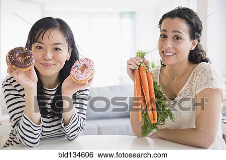 Women choosing between donuts and carrots View Large Photo Image Stock Photograph - Women choosing between donuts and carrots. Fotosearch
