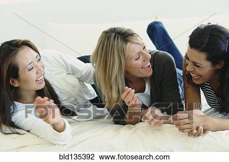 Women relaxing together on bed View Large Photo Image Stock Image - Women relaxing together on bed. Fotosearch