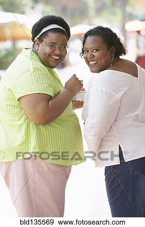 Women smiling together on city street View Large Photo Image Stock Photo - Women smiling together on city street. Fotosearch