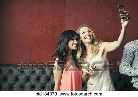 Women taking picture together in nightclub View Large Photo Image Stock Image - Women taking picture together in nightclub. Fotosearch