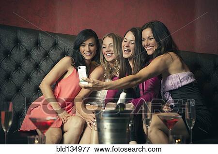 Stock Photo - Women taking picture together in nightclub. Fotosearch