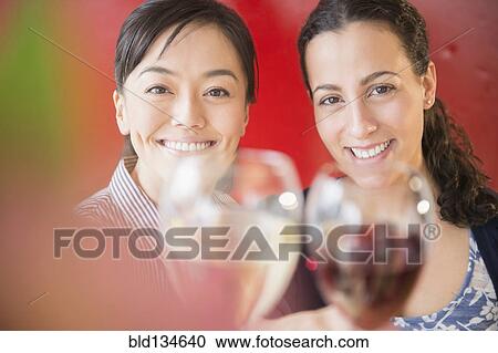 Stock Image - Women toasting each other with wine. Fotosearch