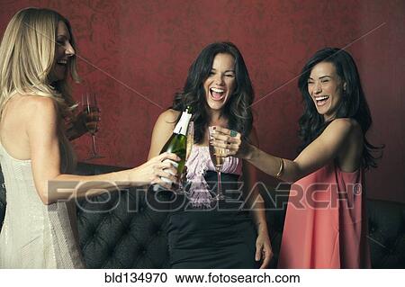 Stock Image - Women toasting with champagne in nightclub. Fotosearch