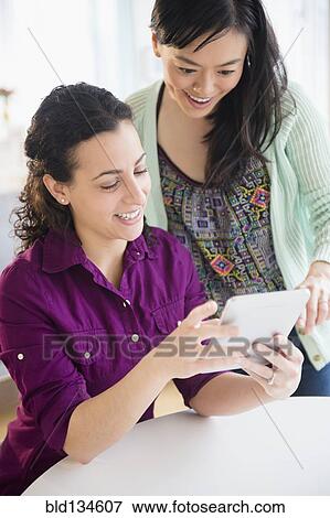 Stock Photo - Women using tablet computer together. Fotosearch