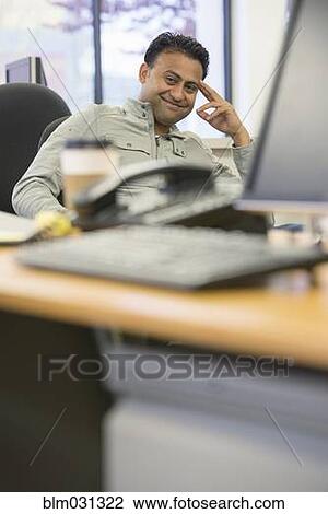Asian businessman smiling at desk in office View Large Photo Image Stock Image - Asian businessman smiling at desk in office. Fotosearch