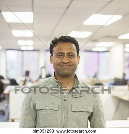 Stock Image - Asian businessman smiling in office. Fotosearch