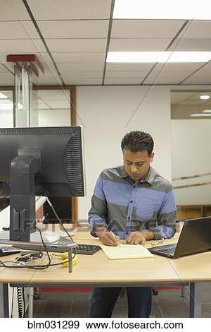 Stock Photo - Asian businessman working at desk in office. Fotosearch