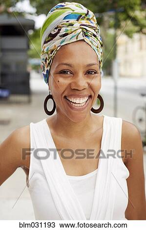 Stock Image - Black woman smiling on city street. Fotosearch