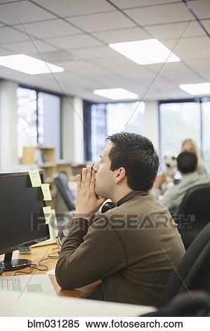 Stock Photography - Businessman thinking at desk in office. Fotosearch