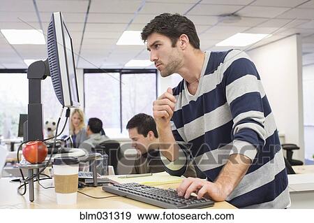 Stock Photo - Businessman working at desk in office. Fotosearch
