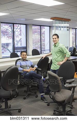 Stock Image - Businessmen smiling in conference room. Fotosearch