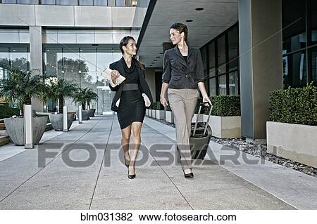 Stock Image - Businesswomen walking together outdoors. Fotosearch