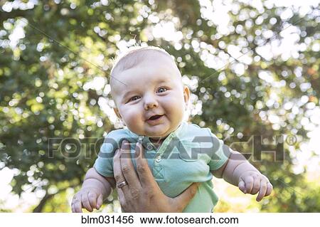 Stock Photograph - Caucasian baby lifted in air outdoors. Fotosearch