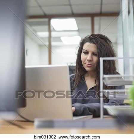 Stock Image - Caucasian businesswoman using laptop in office. Fotosearch