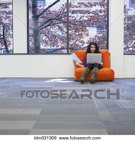 Stock Photo - Caucasian businesswoman working in armchair in office. Fotosearch