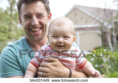 Stock Photo - Caucasian father holding baby outdoors. Fotosearch
