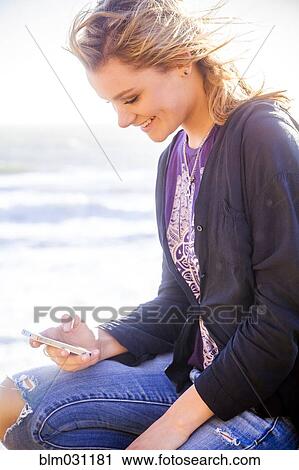 Stock Image - Caucasian girl using cell phone outdoors. Fotosearch