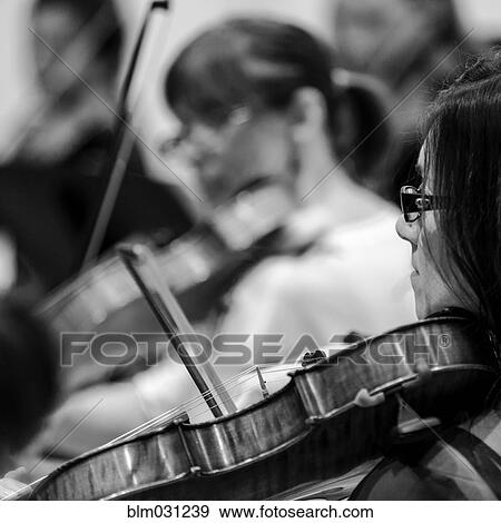 Stock Photo - Caucasian student playing violin in college orchestra. Fotosearch