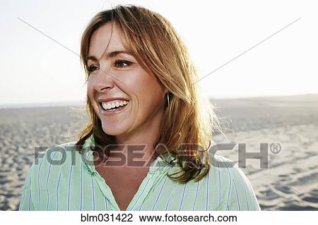Stock Image - Caucasian woman smiling on beach. Fotosearch