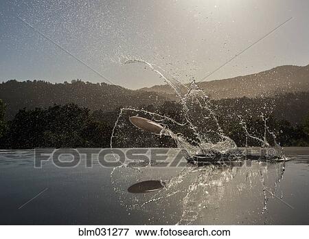 Stock Photo - Fish splashing out of still rural lake. Fotosearch