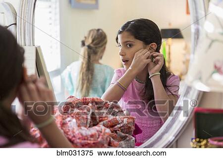 Girls putting on earrings in bedroom View Large Photo Image Stock Photography - Girls putting on earrings in bedroom. Fotosearch