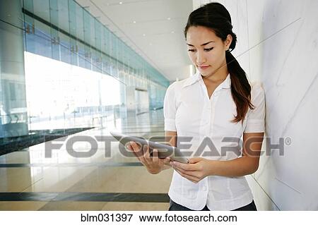 Mixed race businesswoman using tablet computer in lobby View Large Photo Image Stock Photo - Mixed race businesswoman using tablet computer in lobby. Fotosearch