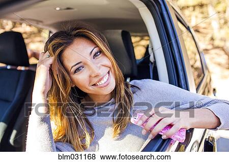 Mixed race woman holding cell phone in car View Large Photo Image Stock Photo - Mixed race woman holding cell phone in car. Fotosearch