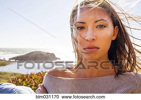 Stock Image - Mixed race woman's hair blowing in wind on coastal hillside. Fotosearch