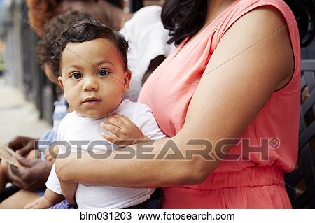 Stock Image - Mother holding toddler son on lap outdoors. Fotosearch