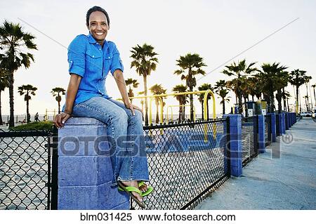 Stock Photography - Older Black woman relaxing by park on beach. Fotosearch