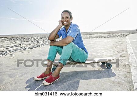 Older Black woman sitting on skateboard on beach View Large Photo Image Stock Photograph - Older Black woman sitting on skateboard on beach. Fotosearch