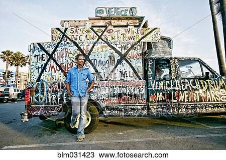 Stock Image - Older Black woman standing by decorated truck. Fotosearch
