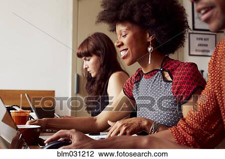 Stock Image - People using technology in coffee shop. Fotosearch