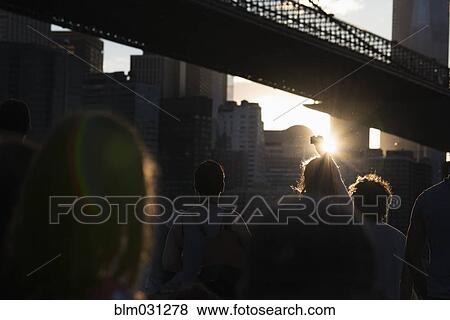 Stock Photo - Silhouette of people walking under urban bridge, New York, New York, United States. Fotosearch