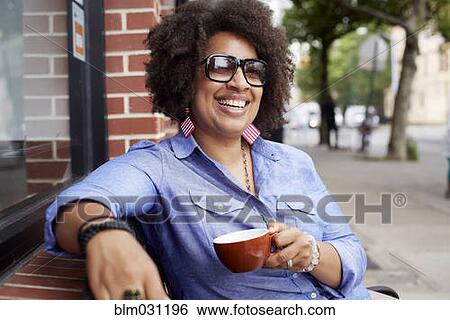 Stock Photograph - Woman having coffee on city street. Fotosearch