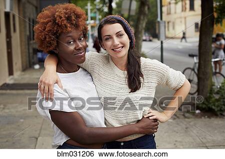 Stock Photograph - Women hugging on city street. Fotosearch