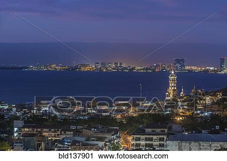 Stock Image - Aerial view of illuminated cityscape and skyline at dusk. Fotosearch