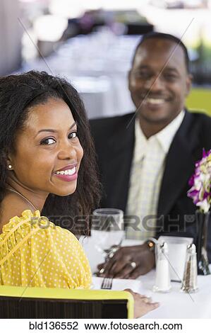 Stock Image - African American couple smiling in restaurant. Fotosearch