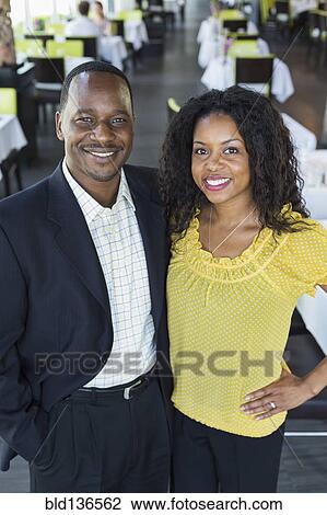 Stock Image - African American couple smiling in restaurant. Fotosearch