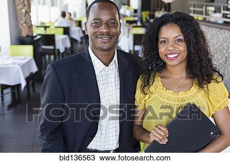 Stock Image - African American couple smiling in restaurant. Fotosearch
