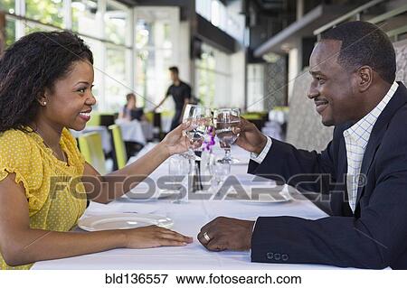 Stock Photo - African American couple toasting each other in restaurant. Fotosearch