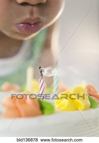 Stock Photo - African American girl blowing out candles on birthday cake. Fotosearch