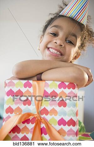 Stock Image - African American girl holding wrapped birthday gift. Fotosearch
