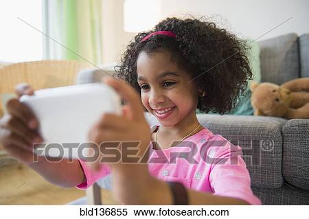 Stock Photography - African American girl taking pictures with cell phone. Fotosearch