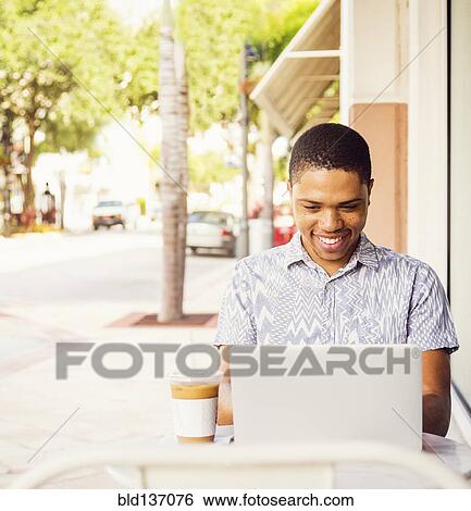 African American man using laptop at sidewalk cafe View Large Photo Image Stock Photograph - African American man using laptop at sidewalk cafe. Fotosearch