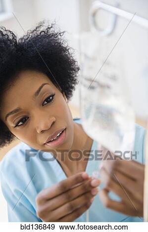 Stock Photo - African American nurse connecting intravenous bag. Fotosearch