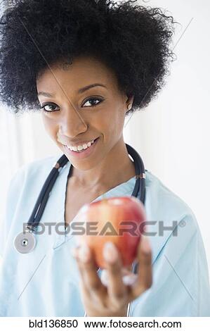 African American nurse holding apple View Large Photo Image Stock Image - African American nurse holding apple. Fotosearch