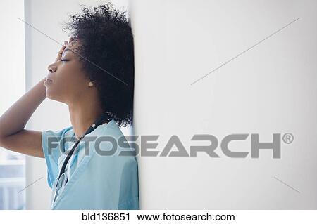 Stock Image - African American nurse leaning against wall. Fotosearch