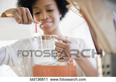 Stock Image - African American woman cooking in kitchen. Fotosearch